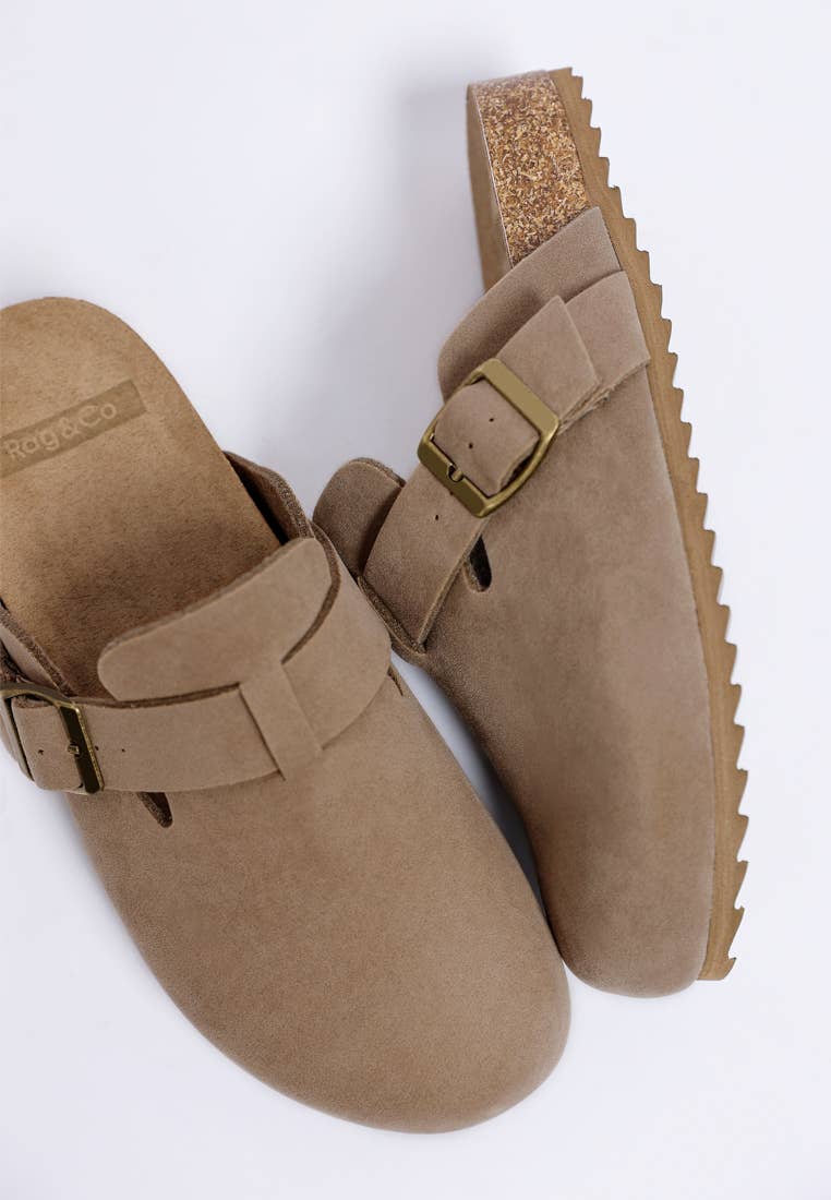 Pair of brown suede clogs with buckles on a white background